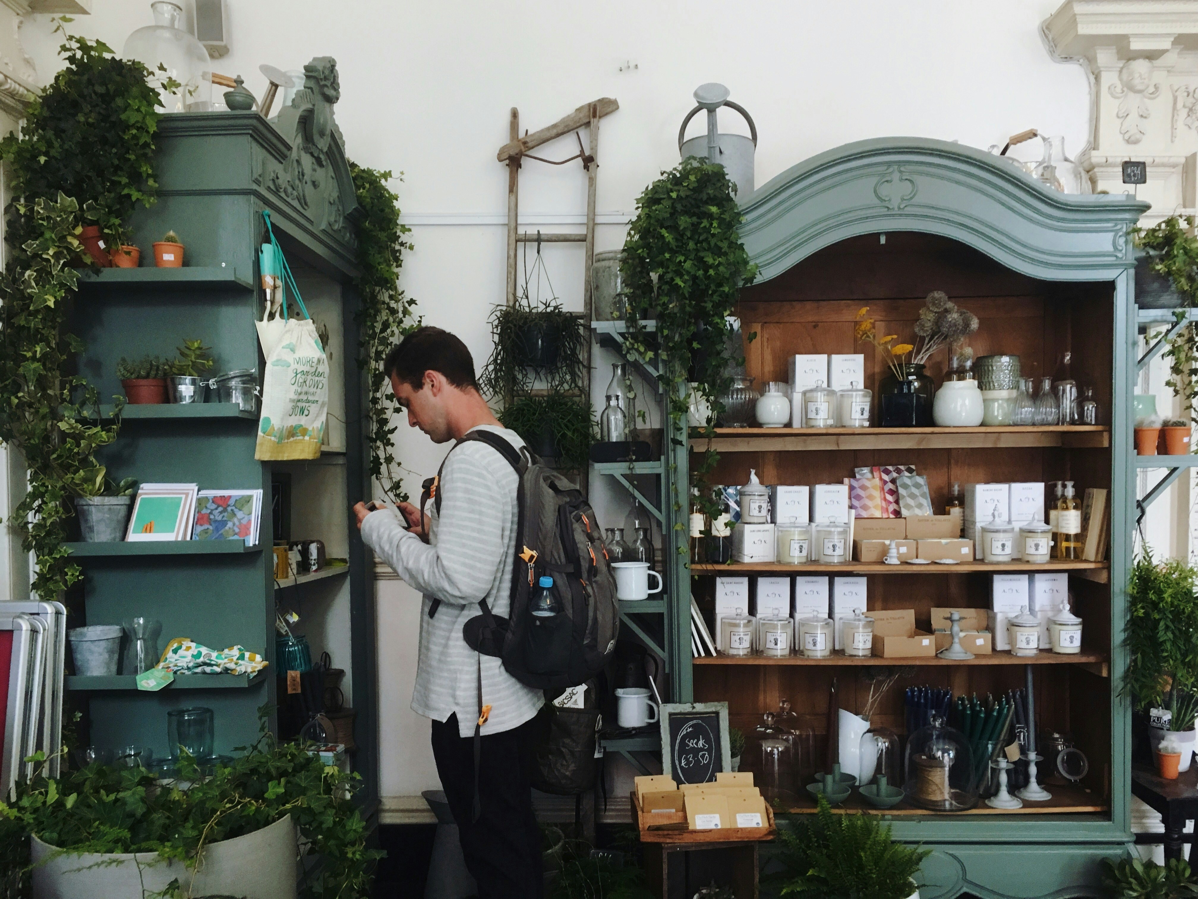 A man with a backpack looks for the perfect gift at a store decorated for the holidays. 