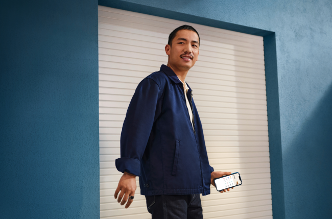 Ein Mann mit einem Handy vor einer blauen Wand.