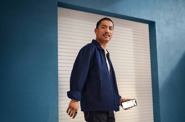 Man in front of blue wall holding a phone. 