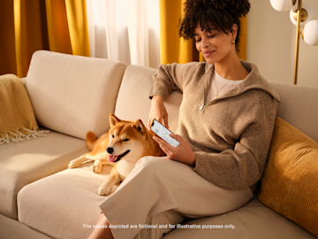 Woman sat is a couch looking in her mobile N26 Crypto features.