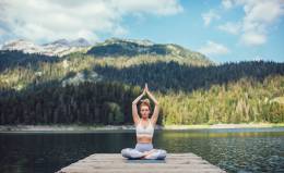 Woman doing yoga on mountain lake.
