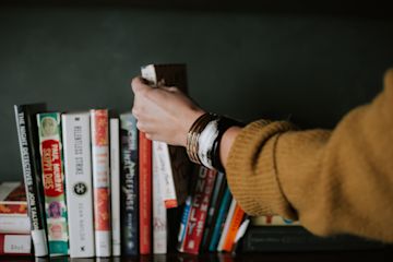 Woman picking a book from a shelve.