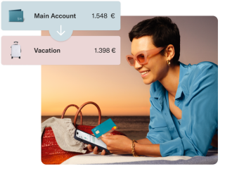 A girl on the beach holding her mobile and N26 card, with a transaction between two N26 Spaces in the foreground.