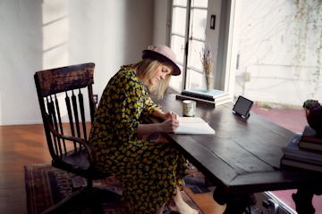 A woman on a desk writing in a notebook.