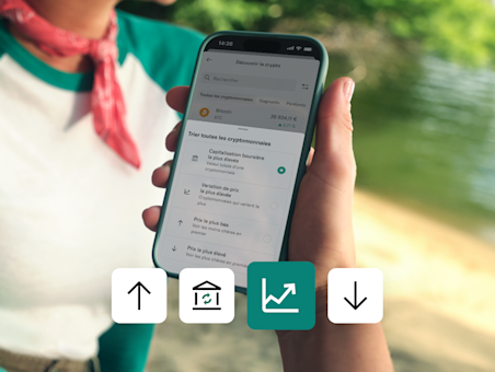 Un smartphone affiche l'écran de trading de crypto avec des options pour trier les pièces par capitalisation ou prix.