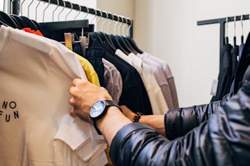 Arms look through clothing rack in a store.