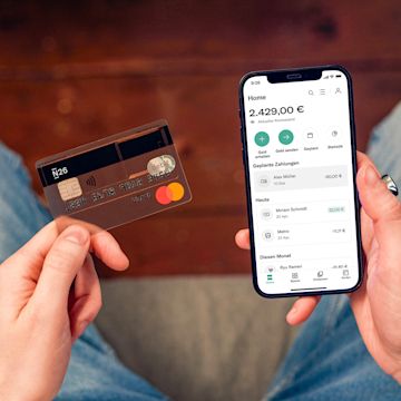 Hände, die ein Smartphone und eine Bankkarte halten.