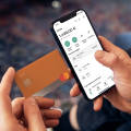 Imagen que muestra a una persona con una tarjeta de débito N26 y la aplicación N26 que muestra la cuenta de la cuenta con la lista de transacciones.