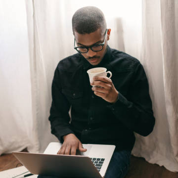 Young man drinks coffee while working on the computer.