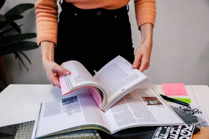 A person leafing a magazine on a table.