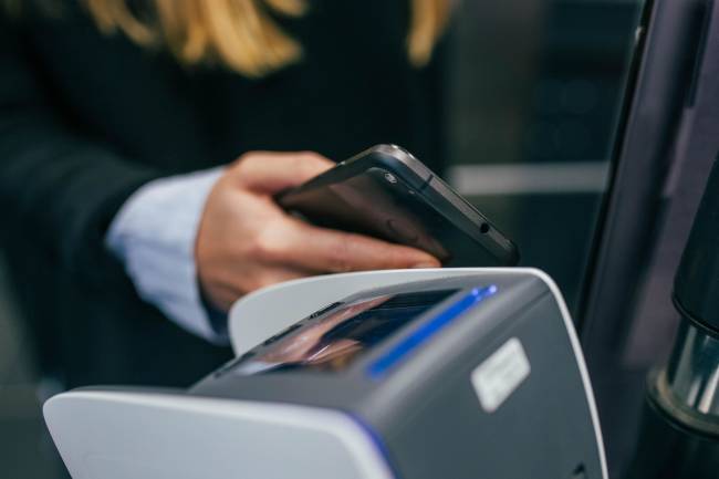 Customer using a mobile to pay in a swipe machine.