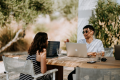 Two people working on laptops outside.