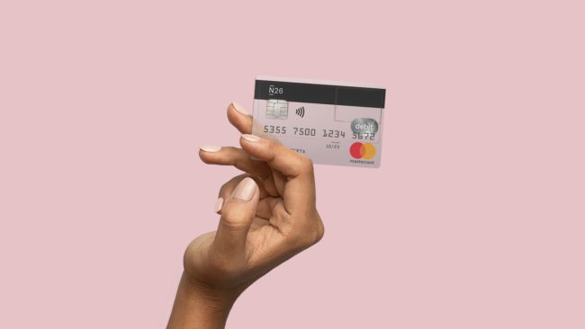 An elevated hand holding a transparent N26 Standard card.