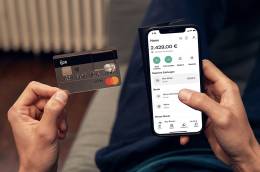 Eine Hand hält eine N26 Bankkarte während die andere Hand ein Smartphone mit der geöffneten N26 App hält. 