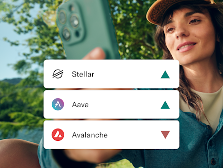 Une femme tient un smartphone, avec des cartes superposées montrant les noms des cryptomonnaies Stellar, Aave et Avalanche.