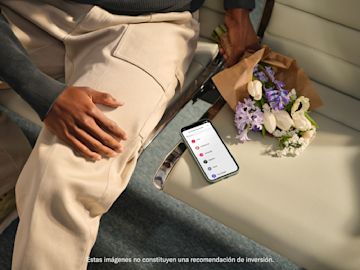 Celular sobre una silla junto a una persona sentada y un ramo de flores.