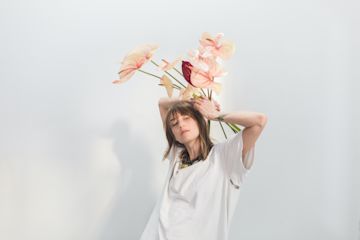 Woman holding flowers over her head.