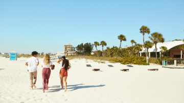 Strand, an dem 2 Frauen und ein Mann entspannt spazieren.