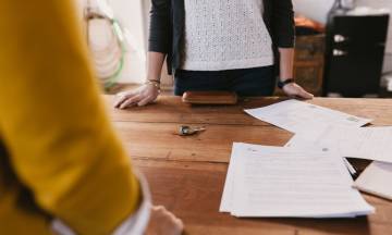 Two freelancers discuss business over a table.