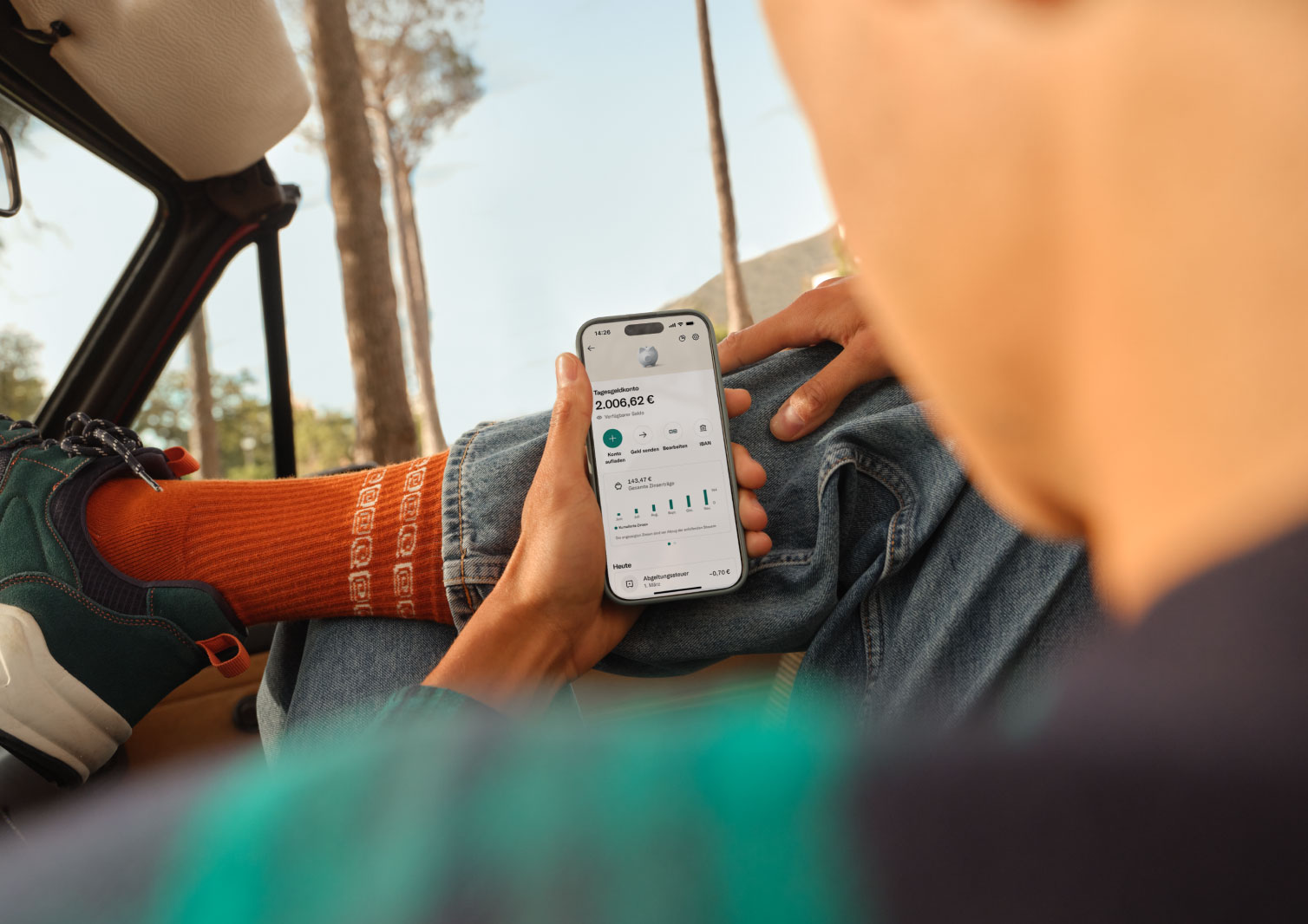 Eine Person hält ein Smartphone, das die N26-Banking-App mit einem verzinsten Konto anzeigt, auf dem ein Kontostand von 2.005,62 € zu sehen ist.