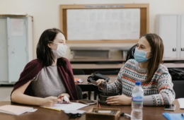 Dos estudiantes Erasmus sentadas en una clase con la mascarilla puesta.