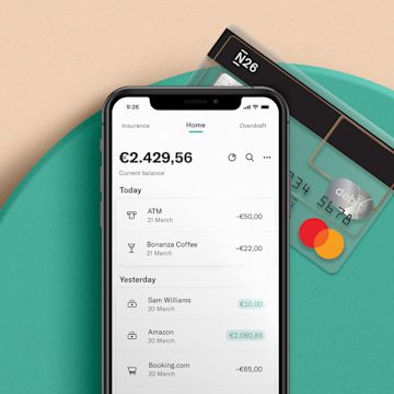 iPhone X laying on a mint colored plate with the N26 Standard card partially under it.