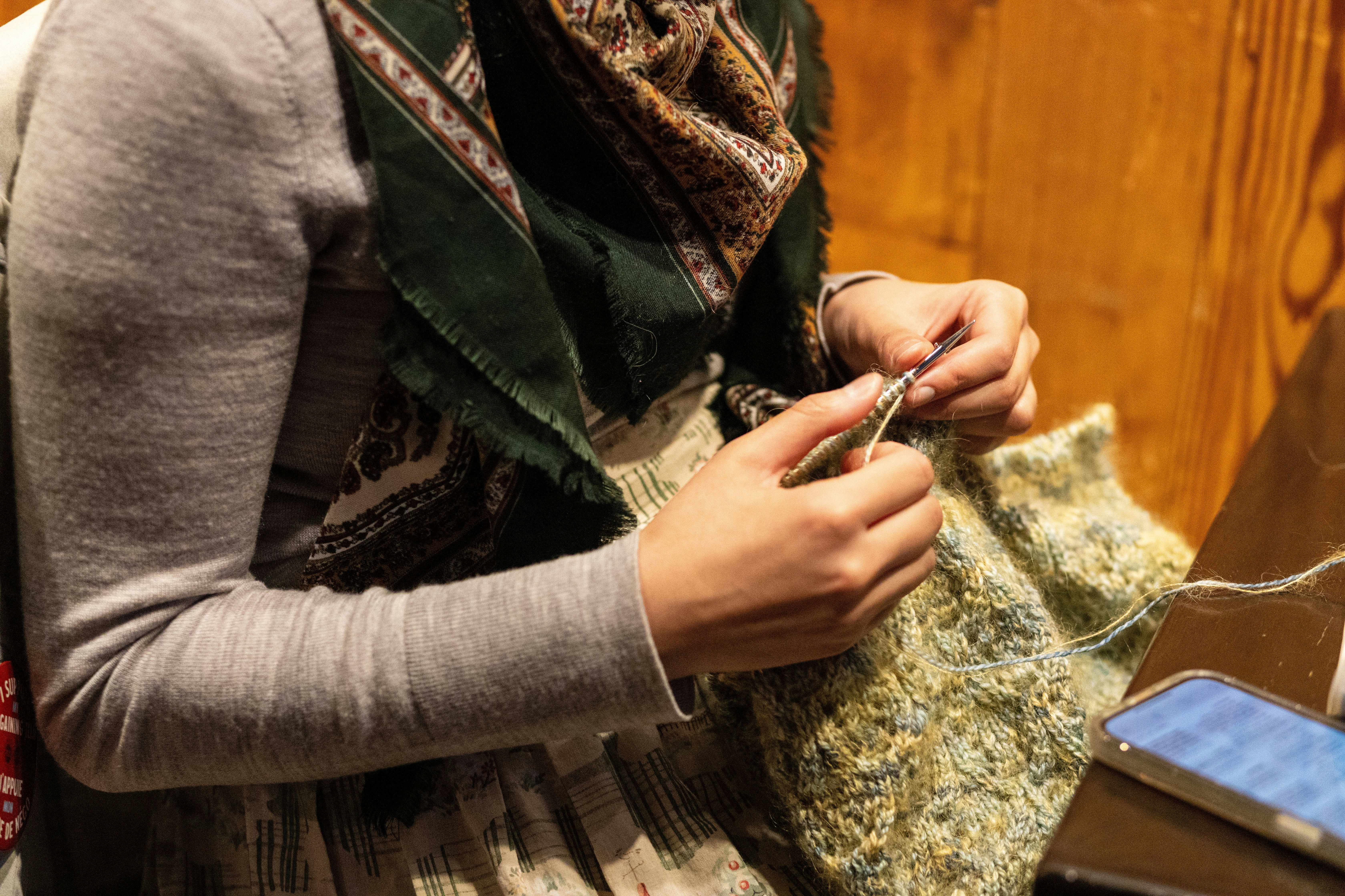 Una persona con una bufanda, tejiendo.