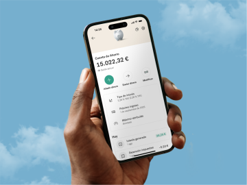 Una mano de un hombre mostrando un móvil con la aplicación bancaria de N26 abierta, con un cielo azul de fondo y el logo de mejor banco del mundo según Forbes.