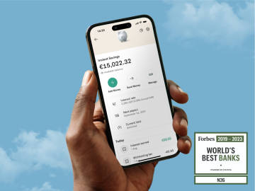A hand of a man showing a cell phone with the N26 banking application open, with a blue sky in the background and the logo of the World Best Banks according to Forbes.