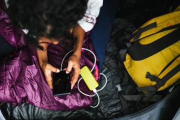 A person using a smartphone in a tent.