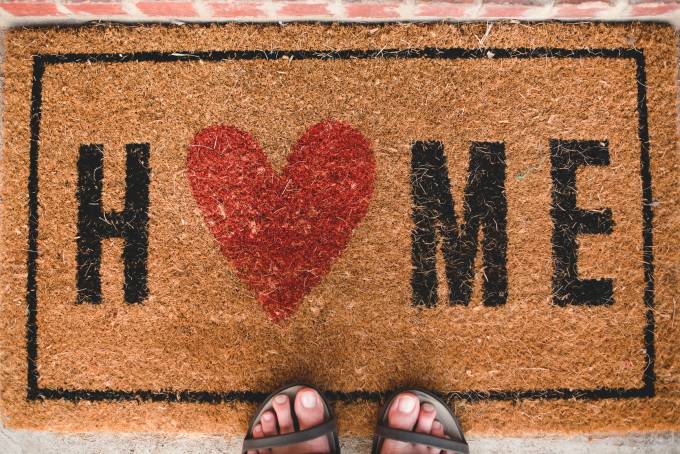 un tapis de maison avec mot "Home" et un coeur rouge au lieu o lettre od.