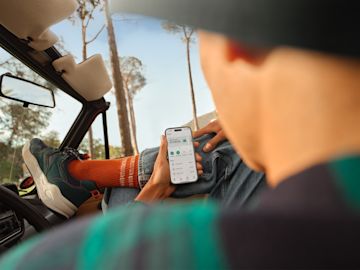 Una persona revisando su saldo bancario en su teléfono en un coche.