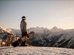 Un snowboarder en una montaña mira hacia el horizonte.