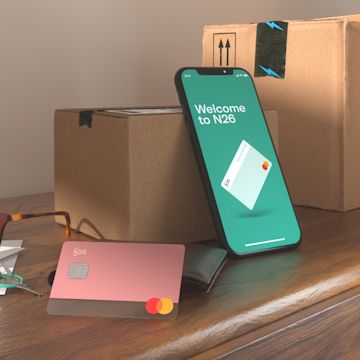 Image of an N26 YOU rose card and N26 APP on a table with with two boxes.