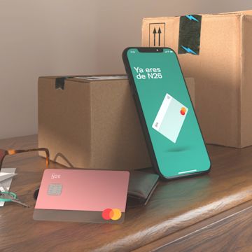 Imagen de una tarjeta rosa N26 YOU y APP N26 en una mesa con dos cajas.