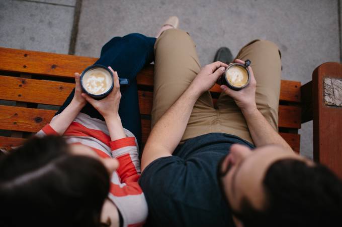 Eine Frau und ein Mann trinken Kaffee auf einer Bank.