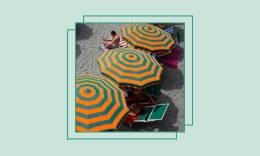 A beach with a row of orange and green striped umbrellas.