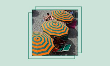 A beach with a row of orange and green striped umbrellas.