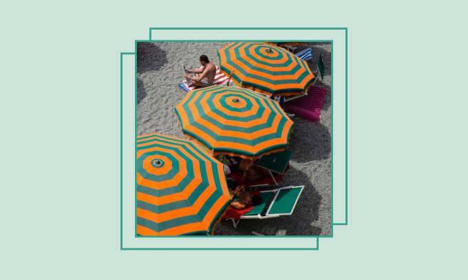Una spiaggia con una fila di ombrelloni a righe arancioni e verdi.