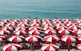 White and red striped parasols on a beach.