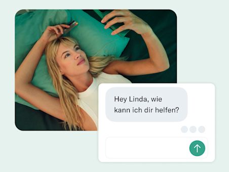 Eine Frau liegt auf einem blaugrünen Bett, im Vordergrund ist eine Grußbotschaft zu sehen.