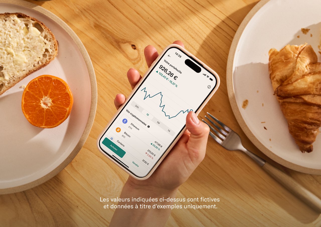 Une main tient un smartphone affichant un portefeuille de cryptomonnaies avec un graphique linéaire et les soldes à l'écran.