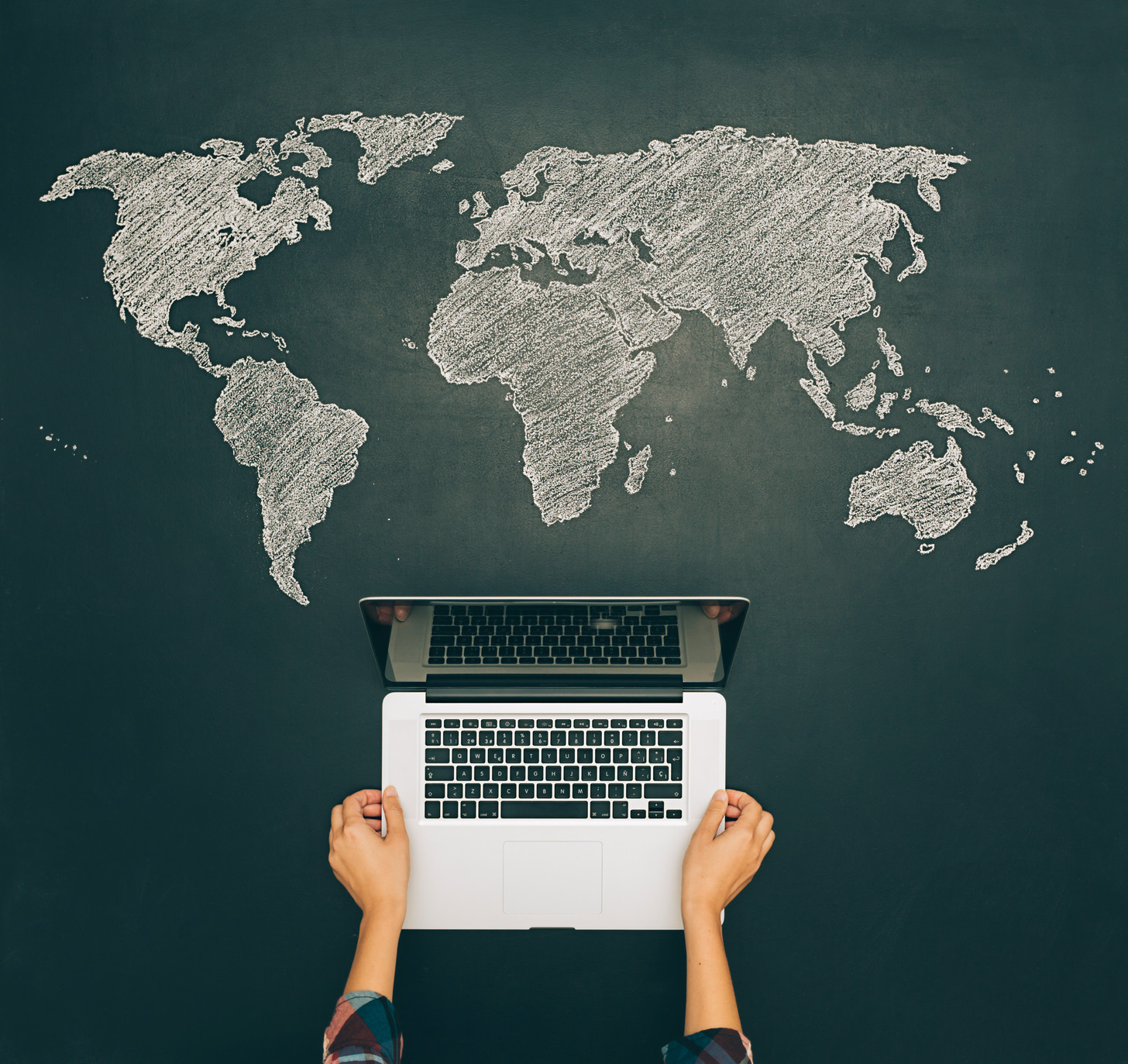map of the world painted on a blackboard and a laptop above the paint.