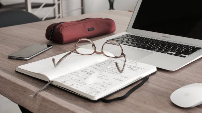 Una libreta con apuntes y unas gafas encima.