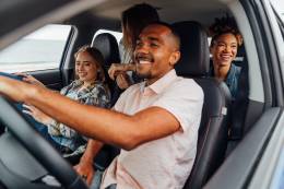 uomo in bianco girocollo t-shirt seduto sul seggiolino per auto con altri 3 amici.