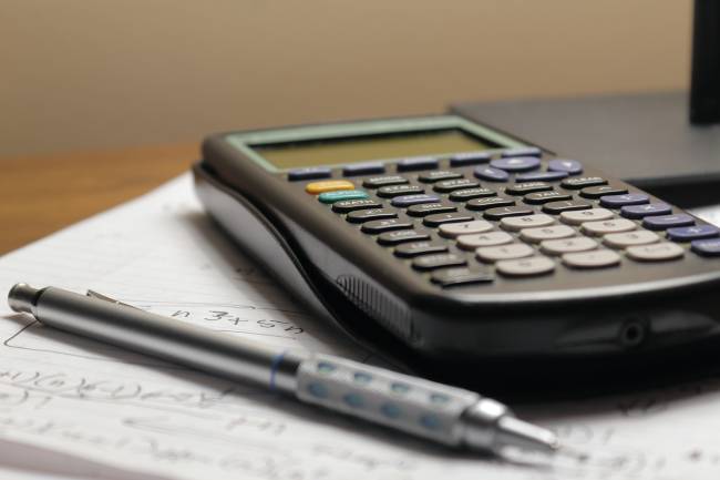 una calcolatrice e una penna appogiati su un quaderno.