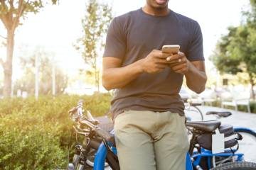 A man sitting on his bike checks his smartphone.