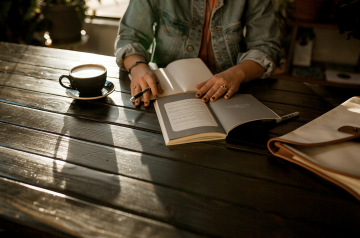 A person taking notes while reading a book.