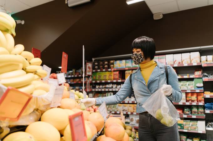 Frau trägt eine Maske Früchte in einem Supermarkt zu kaufen.