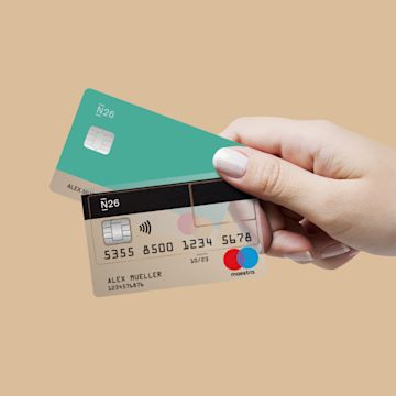 Hands holding N26 You and Maestro card with wheat background.
